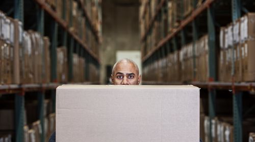 black-warehouse-worker-hidden-cardboard-box-distribution-warehouse